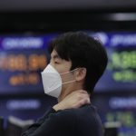 O trader de máscara, operando na bolsa em Seul, Coreia do Sul, simboliza o impacto do coronavírus no mercado financeiro mundial. (Lee Jin-man/ AP Photo)