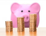 A imagem mostra um porquinho diante de três pilhas de moedas. Ela serve para ilustrar a matéria que fala sobre o mercado financeiro.