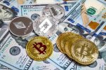 A imagem mostra algumas moedas de bitcoins sobre notas de dólar, e serve para ilustrar a matéria que fala sobre mercado de bitcoins, taxas e outros assuntos.