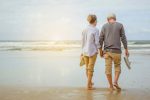 A imagem mostra um casal caminhando à beira da praia com bastante tranquilidade. Ela ilustra o texto sobre como pagar previdência privada.