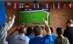Pessoas torcendo e assistindo futebol em uma televisão