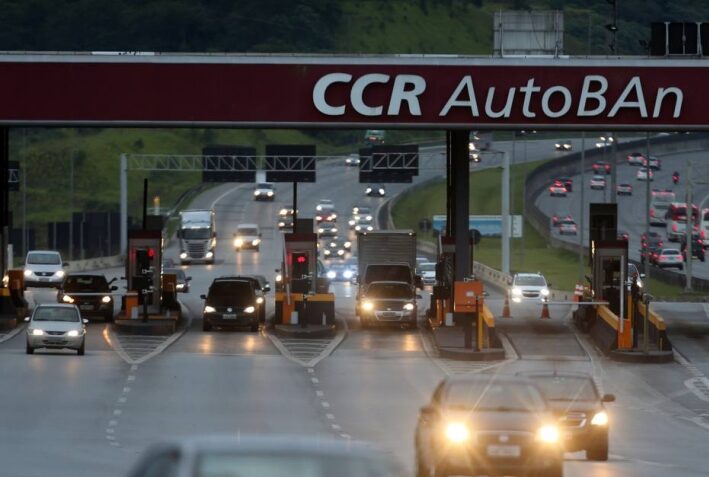 Imagem mostra saída de pedágio da CCR em rodovia, com movimento de veículos.