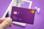 A imagem mostra um cliente segurando o cartão do Nubank, e ele é um dos bancos que permite fazer Pix com cartão de crédito.