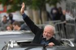 Ex-presidente Lula aparece no teto solar de um carro, acenando e sorrindo