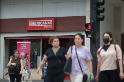 Imagem mostra transeuntes passando por loja da Americanas.