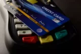 Imagem mostra cartão de crédito apoiado em cima de maquininha de pagamentos.