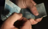 Imagem mostra uma pessoa contando dinheiro.