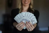 mulher executiva mostra maço de dinheiro nas mãos em primeiro plano