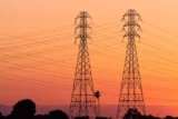 Imagem mostra conjunto de torres de transmissão sob o pôr do sol.