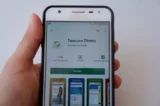 Mão segura smartphone com aplicativo do Tesouro Direto aberto