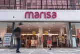 Imagem mostra fachada da loja Marisa com letreiro em destaque e pedestres passando na frente.