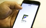 Imagem mostra uma pessoa segurando um celular com o app do FGTS aberto.