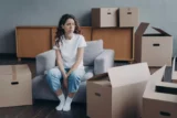 Mulher hispânica se sente difícil de viver sozinha. Jovem moça bonita está cansada de desempacotar caixas.