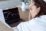 Jovem mulher com laptop cheio de gráficos financeiros na tela mostra stress e fadiga