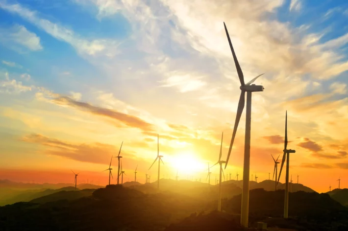 Paisagem ensolarada com moinhos de vendo de usina de energia eólica.