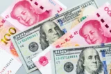 Cédulas intercaladas de yuan e dólar, com os rostos de Mao Zedong e Benjamin Franklin. (Foto: Envato Eelements)
