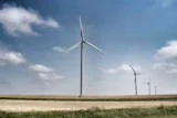Turbina com hélices para energia eólica em meio a terreno agricultável.