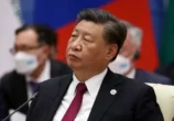 Homem de meia idade chinês veste terno e, com fone no ouvido, se concentra em audiência.