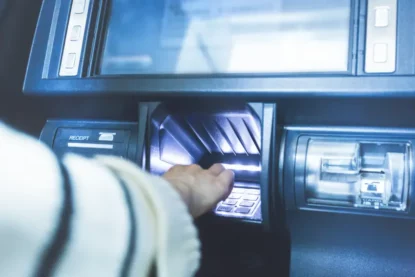 Imagem mostra uma pessoa fazendo operação em terminal bancário de rua.