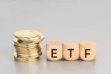 Imagem mostra pilha de moedas ao lado de peças que formam a sigla ETF.