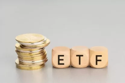 Imagem mostra pilha de moedas ao lado de peças que formam a sigla ETF.