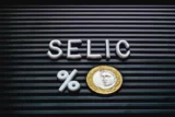 Imagem mostra letreiro com o termo "Selic" junto a uma moeda de R$ 1.