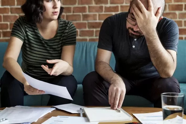 Casal discute contas em meio a expressões de tensão