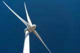 Moinho de vento para geração de energia eólica sob céu azul.