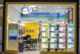 Foto mostra a vitrine da loja de viagens CVC com diversos cartazes coloridos de destinos.