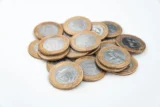 Imagem mostra um punhado de moedas sobre a mesa.