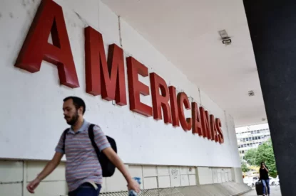 Homem andando em frente à placa da Americanas