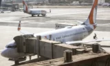 Imagem mostra aeronave no pátio do aeroporto em dia ensolarado.