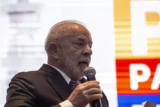 Imagem mostra presidente Lula discursando com um microfone na mão.