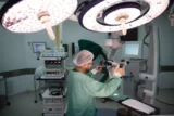 Imagem mostra sala de cirurgia sendo preparada por profissional da saúde.