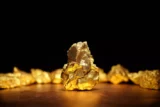 Imagem mostra pepita de ouro reluzente em destaque.