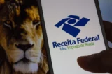 Imagem mostra tela do celular no site da receita com foto de um leão ao fundo.