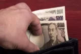 Imagem mostra mão retirando cédulas de iene de carteira.