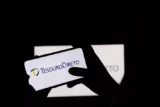 Imagem mostra silhueta de investidor acessando aplicativo do Tesouro Direto no celular.