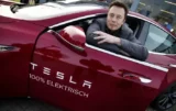 Bilionário Elon Mus posa para foto em janela de carro da Tesla.