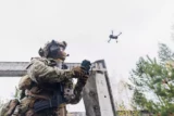Soldado militar controla drone para operação de reconhecimento de posições inimigas. Conceito de guerra inteligente.