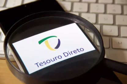 Imagem mostra lupa destacando logo do Tesouro Direto exibido na tela de smartphone.