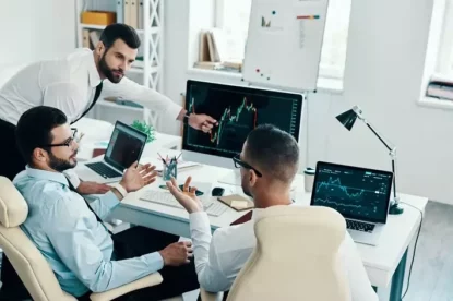 Grupo de jovens modernos em trajes formais trabalhando usando computadores enquanto estão sentados no escritório.