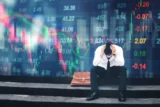 Investidor estressado sentado na calçada em pânico com tela digital de fundo do mercado de ações.