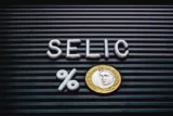 Taxa Selic, economia brasileira. Palavra Selic formada em uma quadro com letras e uma moeda de 1 Real. Dinheiro, Brasil, Economia, investimentos e juros.