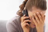 Jovem mulher se estressa durante conversa ao telefone.