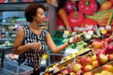 Mulher negra escolhe frutas na mercearia do supermercado.