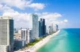 Vista panorâmica de Miami Beach com seus luxuosos apartamentos à beira da praia em um lindo dia de céu azul com nuvens isoladas. (Foto: Kuteich em Adobe Stock)