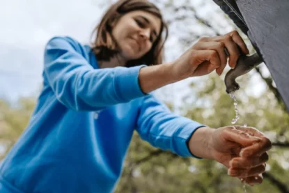 Jovem mulher lava as mãos em uma torneira no quintal. (Foto: Pintau Studio em Adobe Stock)