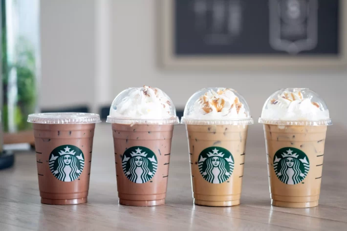 Copos de bebidas geladas da Starbucks enfileiradas sobre mesa. (Imagem: Dontree em Adobe Stock)