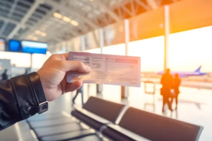 Mão mostrando passagem aérea em aeroporto.